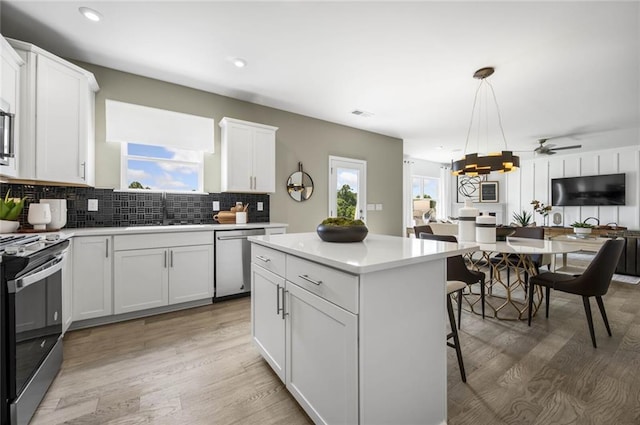 kitchen with a kitchen island, pendant lighting, appliances with stainless steel finishes, a kitchen breakfast bar, and white cabinets