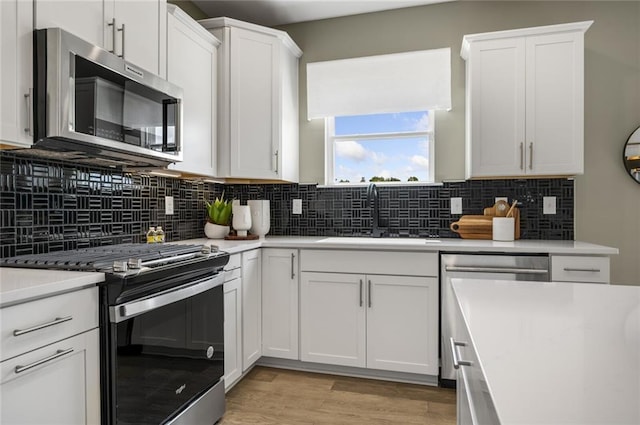 kitchen featuring stainless steel appliances, light hardwood / wood-style floors, white cabinetry, and sink