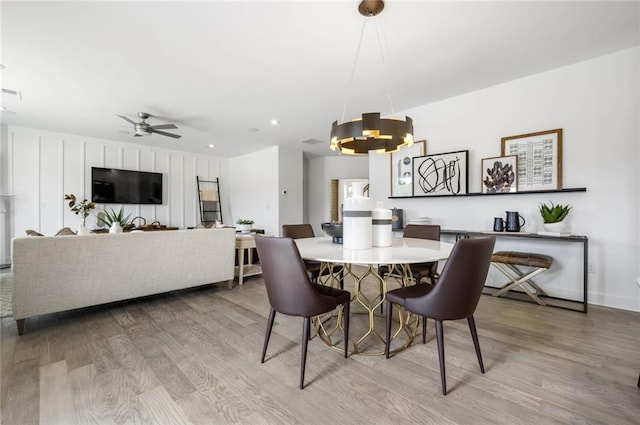 dining space featuring ceiling fan with notable chandelier and light hardwood / wood-style floors