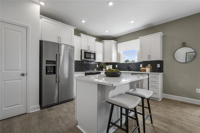 kitchen featuring appliances with stainless steel finishes, a kitchen bar, white cabinets, and a kitchen island