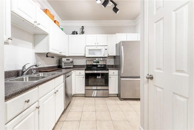 kitchen with light tile patterned flooring, ornamental molding, stainless steel appliances, dark countertops, and a sink