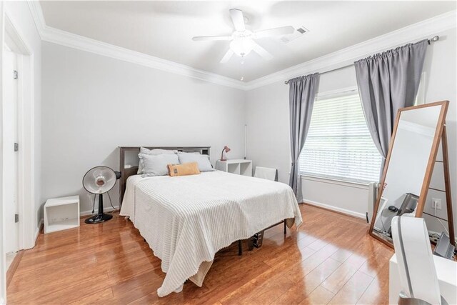 bedroom with light hardwood / wood-style floors, ornamental molding, and ceiling fan