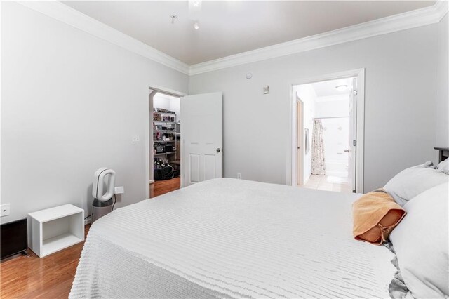 bedroom featuring wood-type flooring, connected bathroom, and crown molding