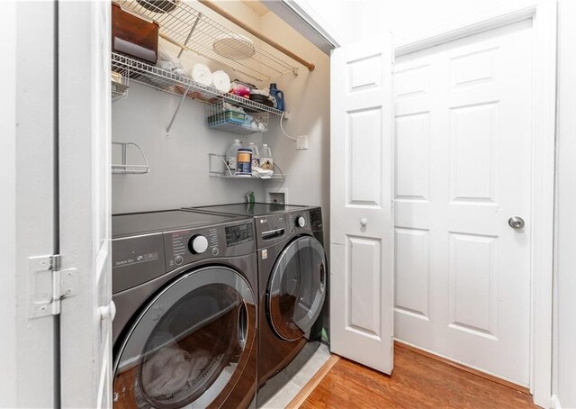 clothes washing area with light wood-type flooring and washing machine and dryer