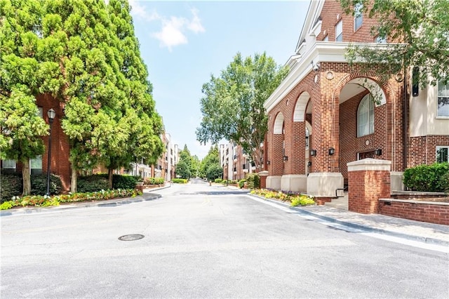 view of street featuring sidewalks, street lights, curbs, and a residential view