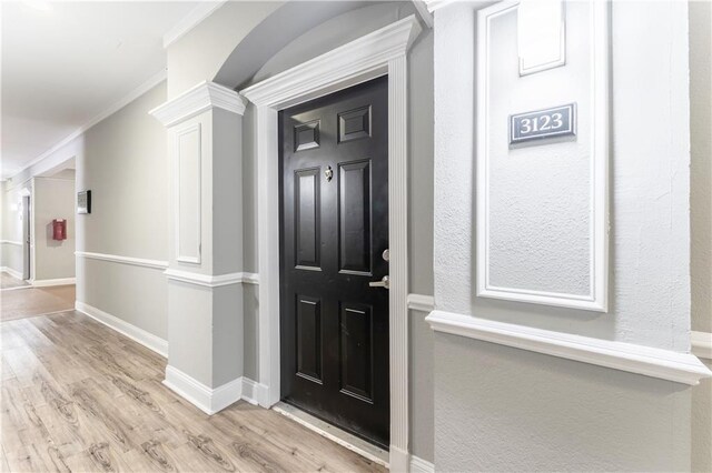 foyer entrance featuring ornamental molding, light hardwood / wood-style flooring, and ornate columns