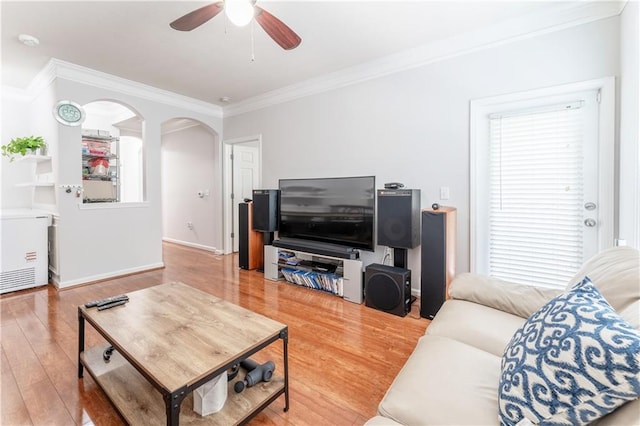 living area featuring ornamental molding, baseboards, arched walkways, a ceiling fan, and wood finished floors