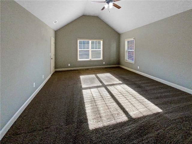 spare room with ceiling fan, dark carpet, and vaulted ceiling