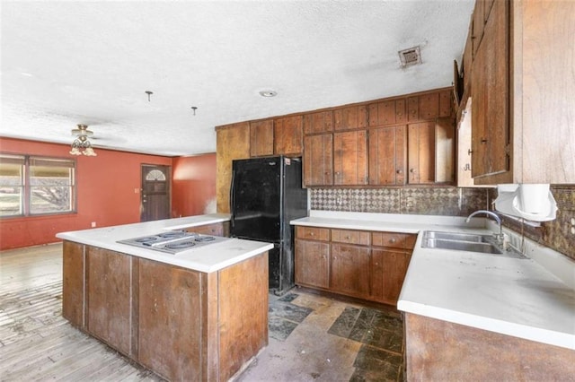 kitchen with stainless steel gas stovetop, decorative backsplash, a center island, sink, and black fridge