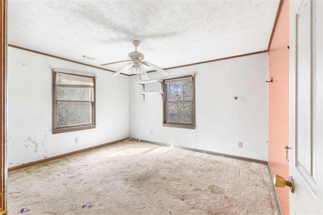 carpeted spare room with a textured ceiling, ceiling fan, crown molding, and a wealth of natural light