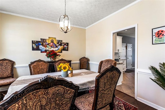 dining space with a textured ceiling, dark wood-type flooring, a notable chandelier, and crown molding