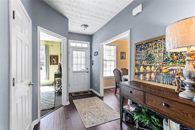 foyer entrance featuring dark wood-style floors, baseboards, and a textured ceiling