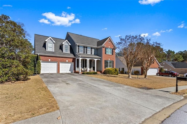 colonial home with a garage, a front yard, brick siding, and driveway