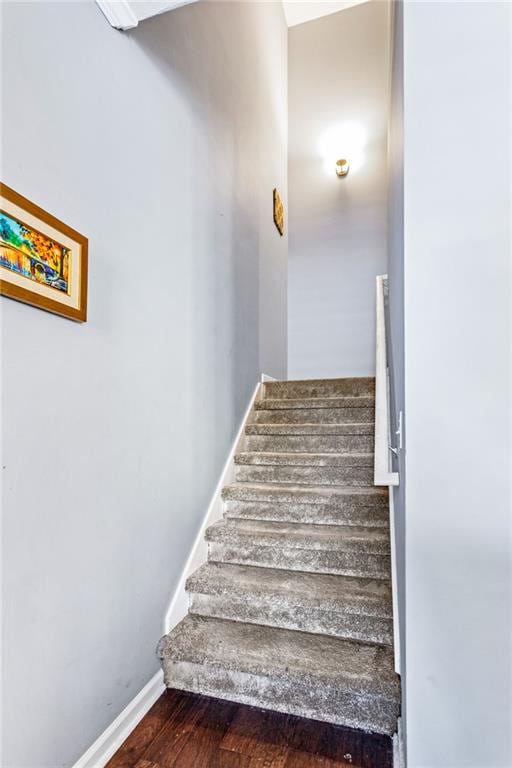 staircase featuring baseboards and wood finished floors