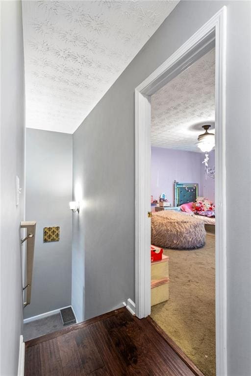 interior space featuring a textured ceiling, hardwood / wood-style flooring, and baseboards