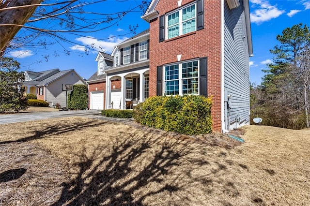 traditional-style house featuring a garage, covered porch, brick siding, and driveway