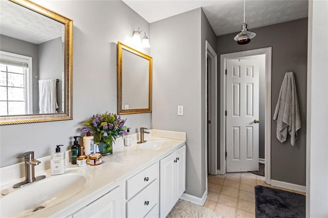 bathroom featuring a sink, a textured ceiling, baseboards, and double vanity