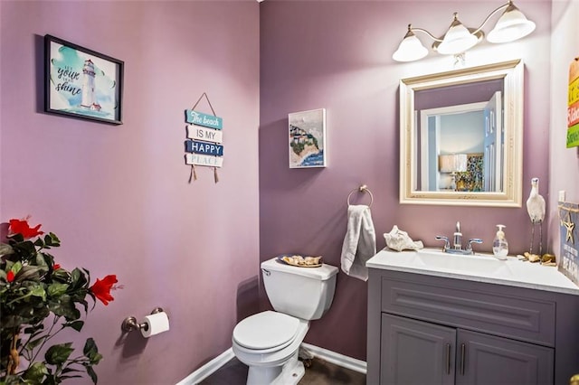 bathroom featuring baseboards, vanity, and toilet