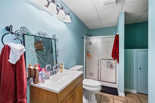 full bath featuring toilet, an enclosed shower, a drop ceiling, and tile patterned floors