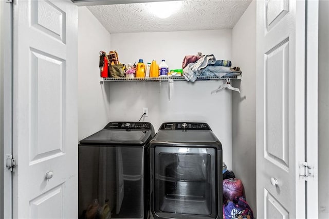 washroom featuring laundry area, a textured ceiling, and washer and dryer