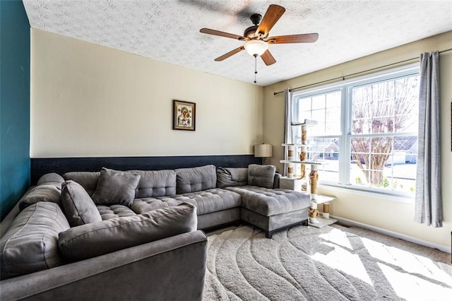 carpeted living room featuring baseboards, a ceiling fan, and a textured ceiling