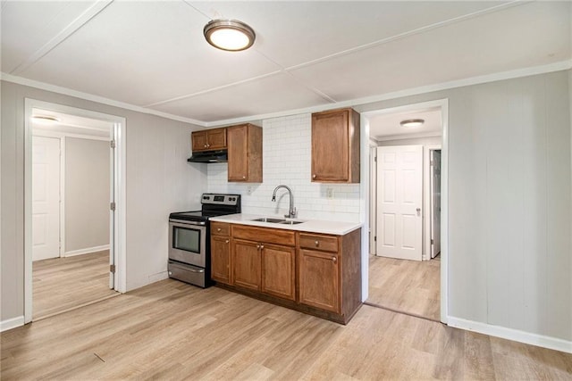 1186 Eastview Rd NE, Conyers, GA 30012 - kitchen with stainless steel range with electric stovetop, under cabinet range hood, light wood finished floors, brown cabinetry, and crown molding
