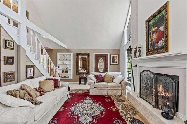 living room featuring high vaulted ceiling, a warm lit fireplace, visible vents, and ceiling fan