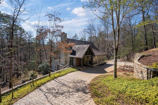 view of home's exterior featuring roof with shingles, decorative driveway, and a chimney