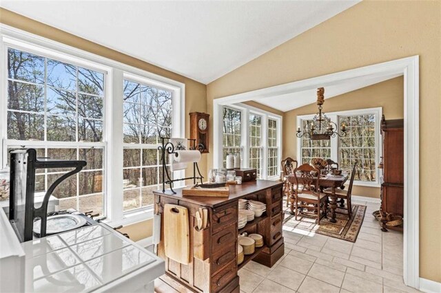 dining area featuring a healthy amount of sunlight, vaulted ceiling, baseboards, and light tile patterned floors