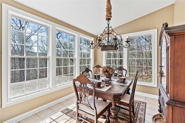 kitchen with light tile patterned floors, baseboards, lofted ceiling, decorative light fixtures, and white dishwasher