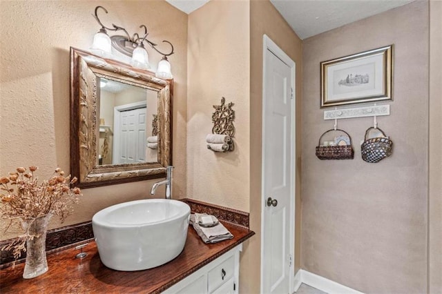 bathroom featuring a textured wall, baseboards, and vanity