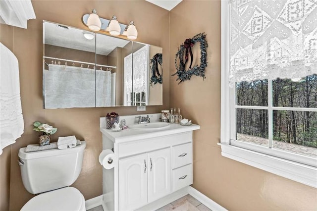 bathroom with toilet, curtained shower, baseboards, and vanity