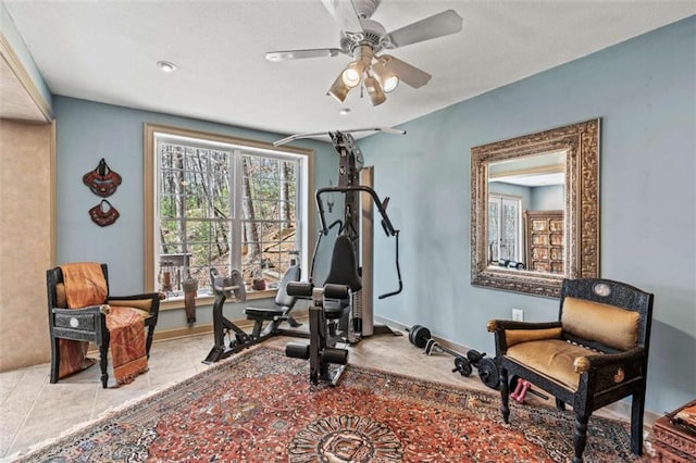 workout room with ceiling fan, tile patterned flooring, and baseboards