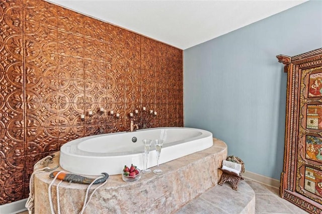 bathroom with tile patterned flooring, a bath, and baseboards