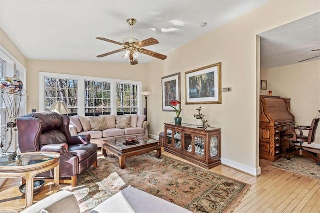 living room featuring light wood-style floors, baseboards, and a ceiling fan