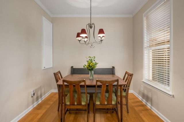 dining room featuring a chandelier, ornamental molding, light wood-style flooring, and baseboards
