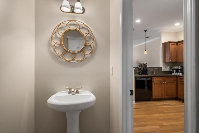 bathroom with a sink, recessed lighting, wood finished floors, and crown molding