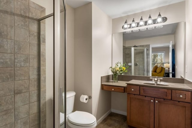 bathroom with toilet, a stall shower, vanity, baseboards, and tile patterned floors
