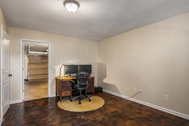 home office featuring concrete floors and baseboards