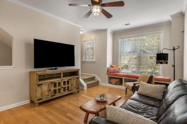 living room with baseboards, ornamental molding, visible vents, and light wood-style floors