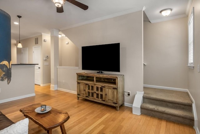 living area with baseboards, ceiling fan, ornamental molding, and light wood-style floors