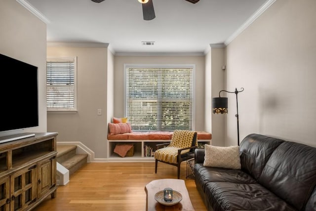 living room with light wood-style flooring, visible vents, ceiling fan, and crown molding