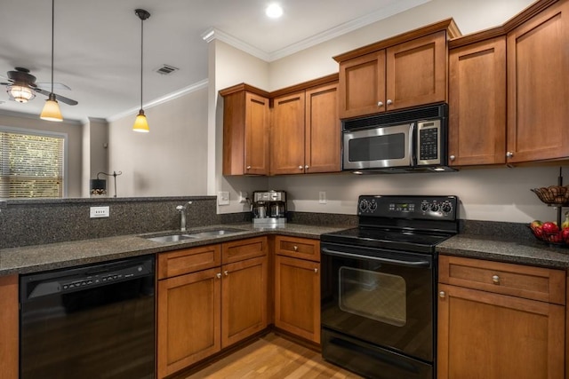 kitchen with black appliances, ornamental molding, brown cabinetry, and a sink