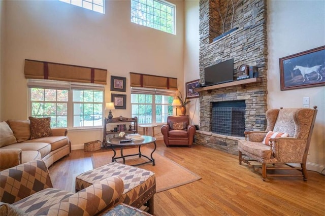 living room featuring a stone fireplace, hardwood / wood-style floors, and a high ceiling