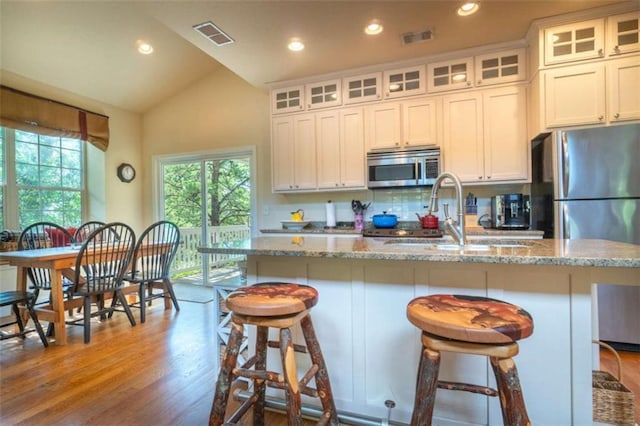 kitchen featuring white cabinetry, sink, stainless steel appliances, and a center island with sink