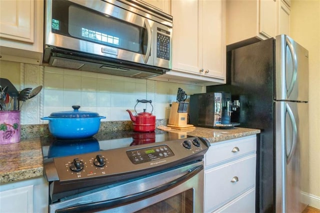 kitchen featuring light stone countertops, appliances with stainless steel finishes, tasteful backsplash, and white cabinetry