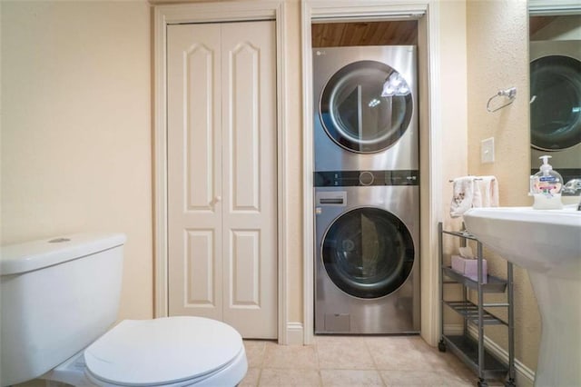 laundry room featuring stacked washer / drying machine and light tile patterned flooring