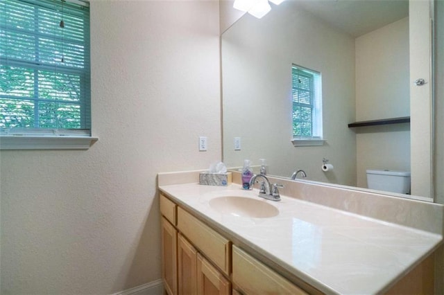 bathroom with a wealth of natural light, vanity, and toilet