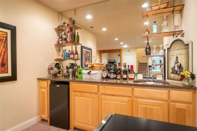 kitchen with dark stone countertops, light carpet, sink, and fridge