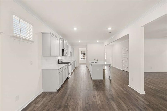 kitchen with an island with sink, appliances with stainless steel finishes, a kitchen breakfast bar, light countertops, and a sink